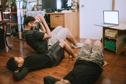 Unos chicos hacen ejercicio con su padre mientras usan una transmisión de vídeo.