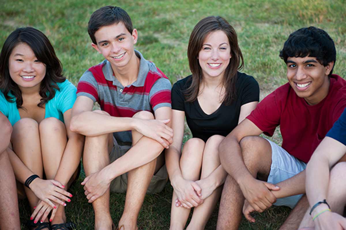 A group of happy Multi-ethnic teenagers outside on grass