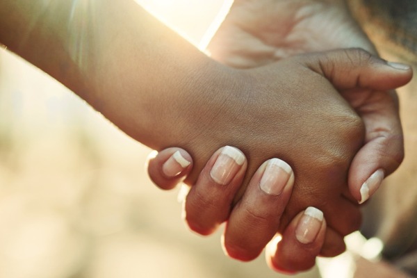 Close-up to two people holding hands.